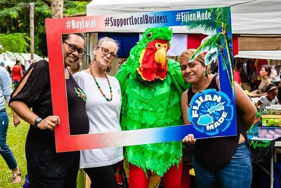 People posing in a large cut out picture frame, one of the people is dressed in a birdsuit.